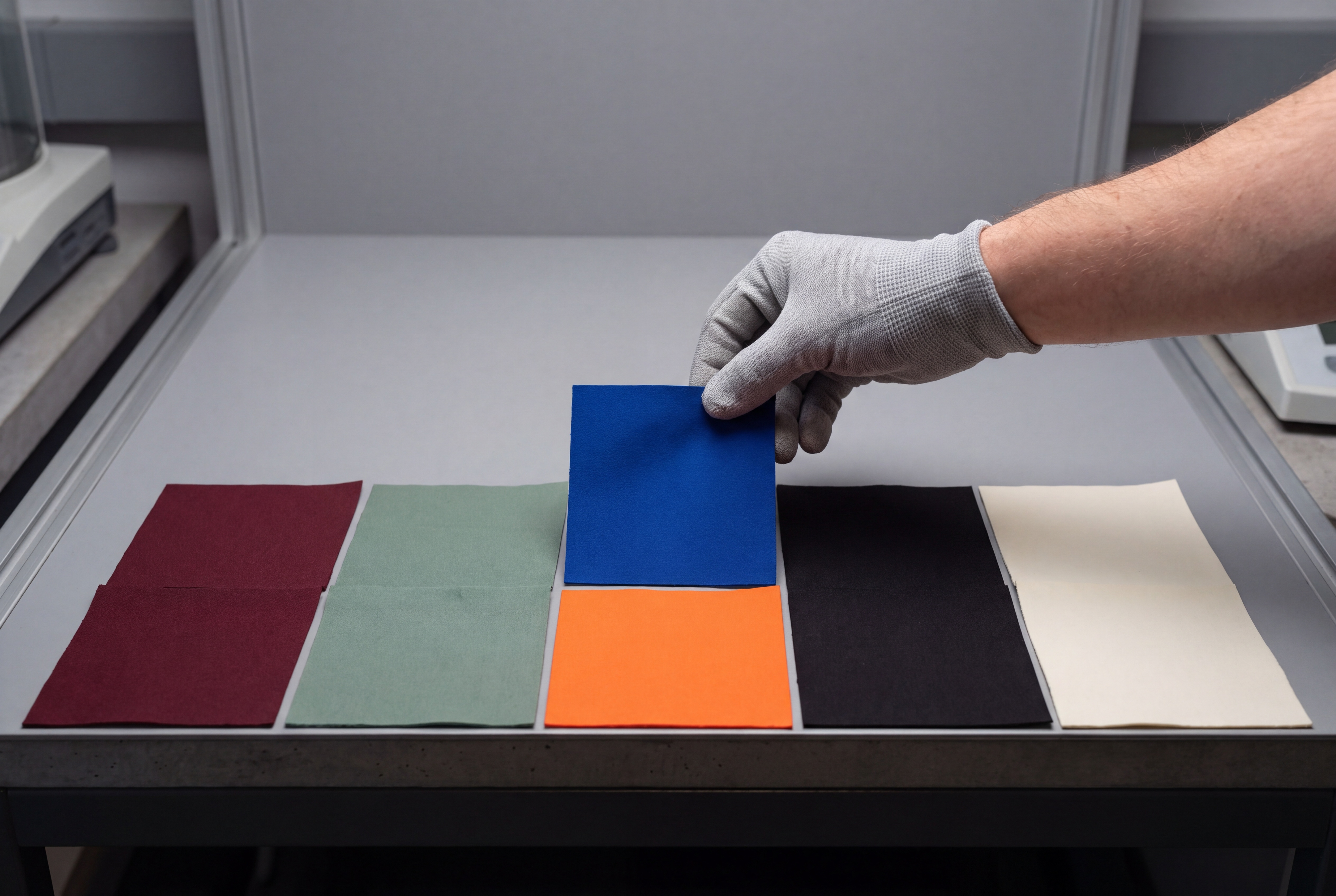 Gloved hand placing a lab-dip swatch beside a colour standard
