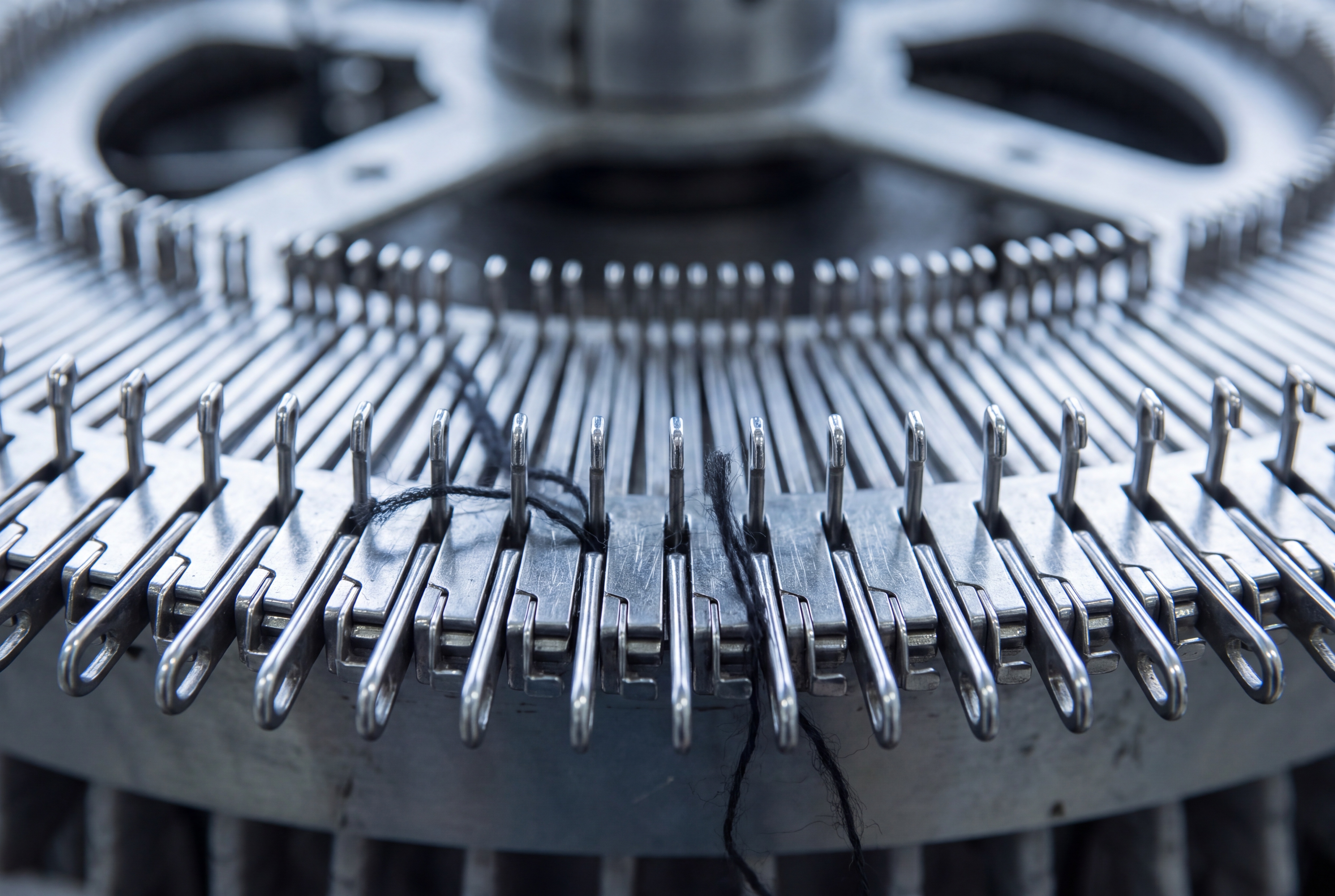 Macro detail of knitting machine needles and yarn
