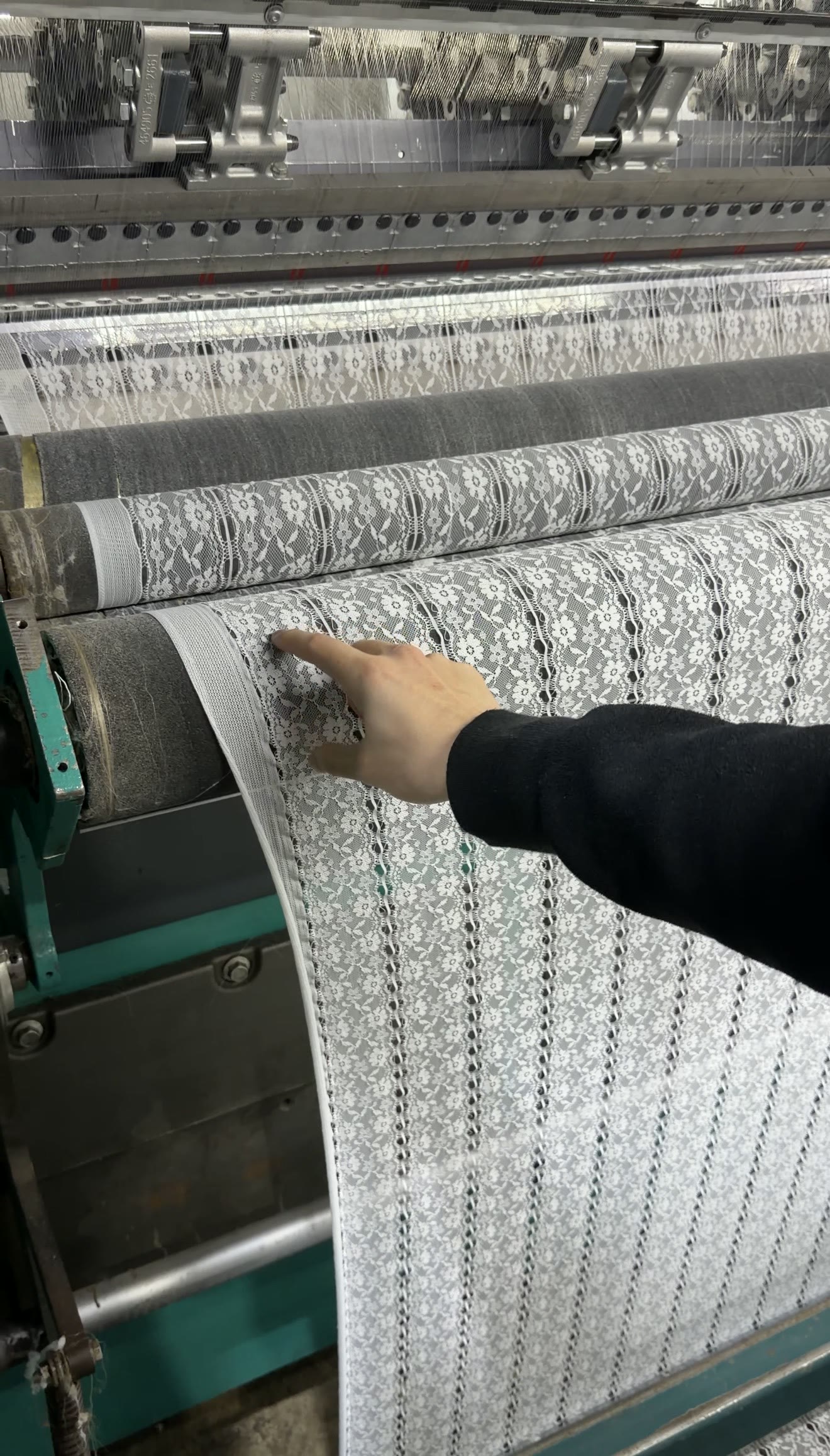 Hand lifting finished lace fabric off a warp-knitting machine on our floor